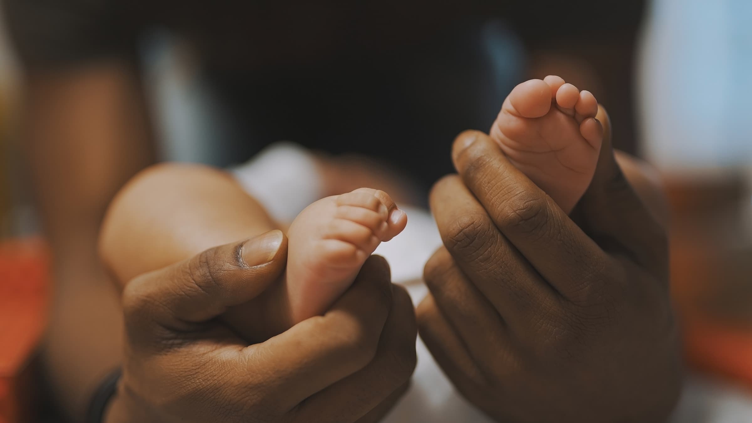 A baby's tiny feet held gently in caring hands